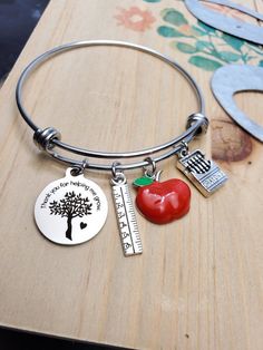 a bracelet with an apple, ruler, and tree on it that says i love my teacher