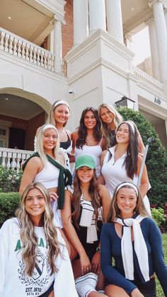 a group of young women standing next to each other in front of a white building