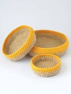 two yellow and beige baskets sitting on top of each other in front of a white background