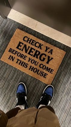 someone standing in front of a door mat that says check ya energy before you come in this house