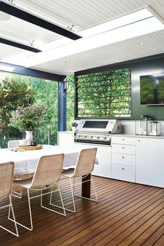 an outdoor kitchen with wood flooring and white table set up for four people to eat