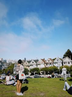 people are sitting on the grass in front of houses