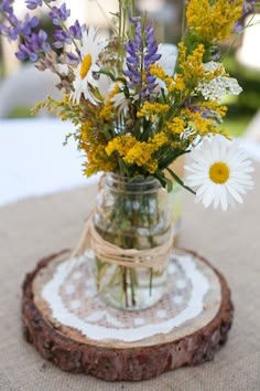 a vase filled with flowers sitting on top of a wooden slice