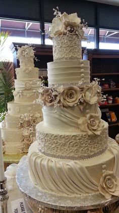 a large white wedding cake sitting on top of a table in front of other cakes