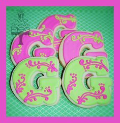 pink and green decorated cookies with the letter g on them are sitting next to each other