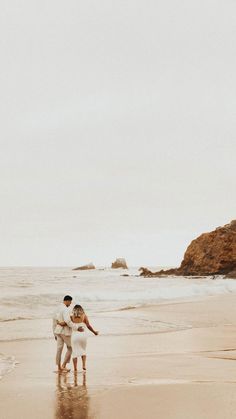 two people standing on the beach holding hands