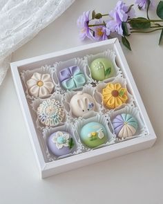 a box filled with lots of different colored candies on top of a white table