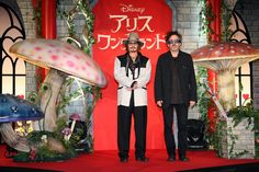 two people standing on a red carpet in front of mushrooms and toades at the disney japan event