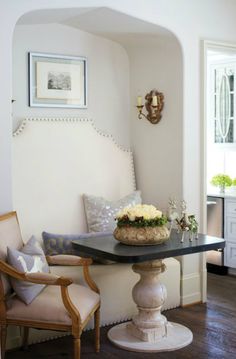 a room with a table, chairs and pictures hanging on the wall above it's headboard