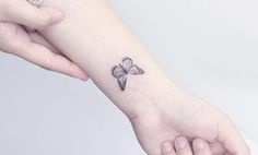 a small butterfly tattoo on the left inner forearm and wrist, is shown in black ink