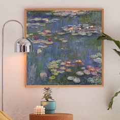 a painting hanging on the wall next to a table with candles and a potted plant