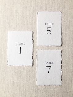 four pieces of paper with numbers on them sitting on top of a white table cloth