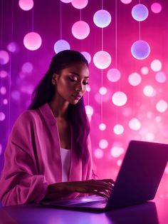 a woman sitting at a table with a laptop computer in front of her and colorful lights hanging from the ceiling behind her