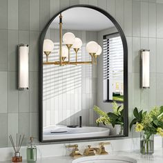 a bathroom with a sink, mirror and flowers in vases on the counter top