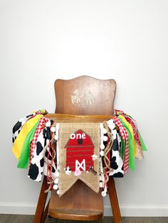 a wooden chair with a cow print banner on it's back sitting in front of a white wall