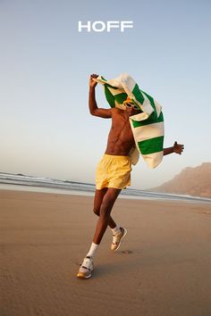 a man running on the beach with a towel over his head