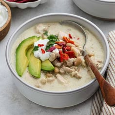 a white bowl filled with soup and topped with avocado