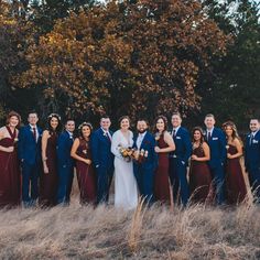 a group of people standing next to each other in front of tall grass and trees