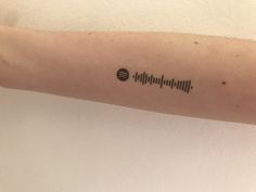 a person's arm with a black and white sound wave tattoo on the left forearm