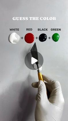 a person is holding a paintbrush and pointing it at the color red, black, green