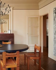 a dining room table with chairs and a chandelier hanging from the ceiling in front of a fireplace