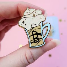 a person holding up a pin with a drink in it's cup on top