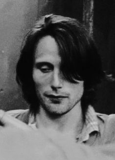 black and white photograph of a man with long hair looking at something in his hand