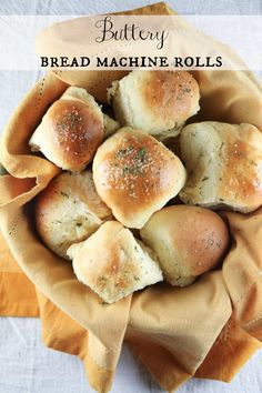 bread machine rolls sitting in a bowl on top of a white table cloth with the words, buttery bread machine rolls