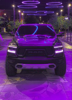 the front end of a purple truck parked in a parking lot with lights above it