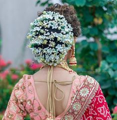 the back of a woman's head with flowers in her hair and jewelry on it