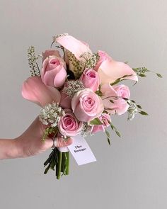 a hand holding a bouquet of pink roses