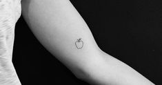 a small apple tattoo on the arm