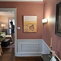 a man standing in a living room next to a painting