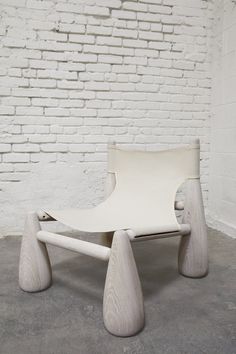 a white chair sitting on top of a cement floor next to a brick wall in an empty room