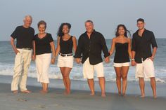 a group of people standing next to each other on top of a beach near the ocean