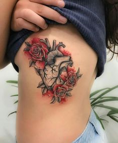 a woman's stomach with roses and a heart tattoo on her side ribcage