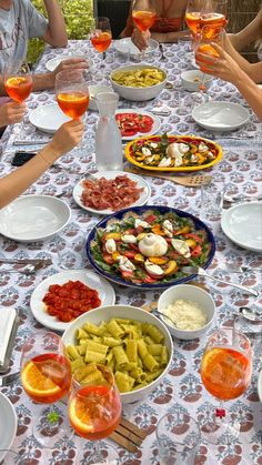 a group of people sitting around a table filled with food