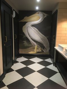 a painting of a pelican on the wall in a bathroom with black and white checkered flooring