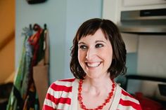 a woman in a red and white striped shirt smiles at the camera while wearing a necklace