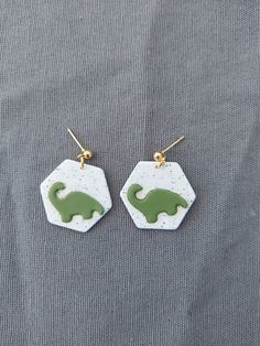 two small green and white earrings with an elephant on the front one has a gold ear hook