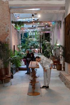 a man standing in front of a table with plants on it and people looking at the ground