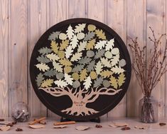 a wooden tree with leaves on it sitting next to some dried flowers and branches in a vase