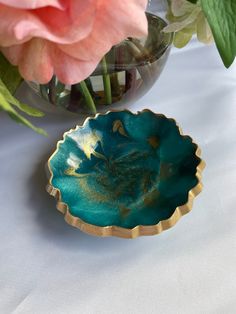 a blue bowl with gold rim sitting on a table next to a pink flower vase