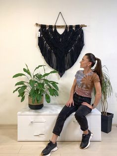 a woman sitting on top of a white table next to a plant and potted plant