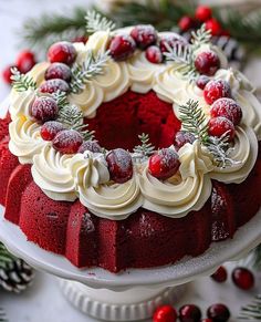 a red velvet cake with white frosting and cranberries on top, surrounded by pine branches