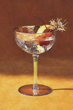 a glass filled with fruit and garnish on top of a yellow tablecloth