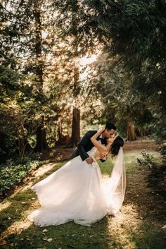 a bride and groom kissing in the woods