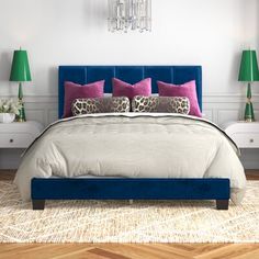 a bedroom with white walls, blue bedding and pink pillows on the headboard