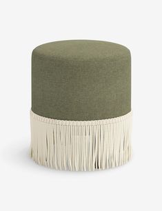 a green and white ottoman with tassels on the bottom, in front of a white background