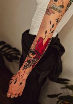 a woman's arm with tattoos on it and a red heart in the middle